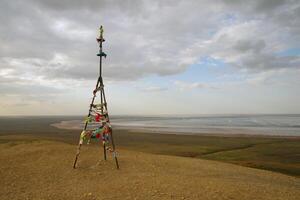 Triangulation mark with buddhist prayer flags near lake Baskunchak photo