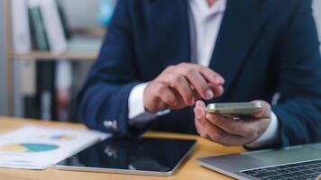 Businessman using smartphone for digital communication or financial analysis at office desk, representing mobile productivity, Technology in business, and online data management. photo