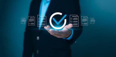 Business person holding a checkmark icon surrounded by document lists, symbolizing successful completion, quality assurance, and compliance. Ideal for approval, verification, and certification. photo