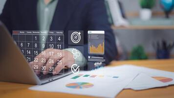 Hand on laptop with digital calendar, target, charts. Symbolizes digital scheduling, project planning, goal setting. Ideal for business management, productivity, data analysis, strategic execution now photo