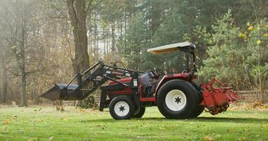 Modern agricultural tractor with a canopy above the driver's seat stands on a farm on an autumn sunny day, there are no people in the photo