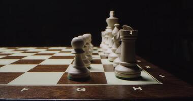White chess pieces are lined up in even rows on a game board, ready for a game, close up photo
