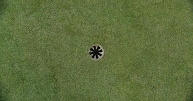View of a golf course set on artificial turf. The golf ball rolls up to the hole and spins around its circumference photo