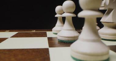 White chess pieces lined up in even rows on a game board, ready for a game photo