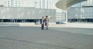 Business women talking to each other and drinking coffee while walking through the business center of a modern city, on a sunny autumn day photo