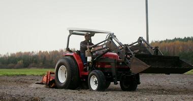 Male farmer controls the quality of plowing the land by driving a multipurpose agricultural machine, on an autumn day photo