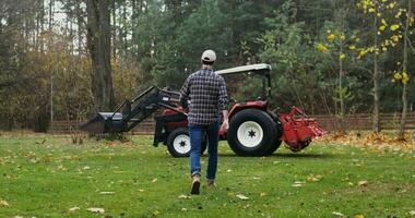 Male farmer getting ready to start work in the field on an autumn day, getting into a modern agricultural tractor and starting it photo