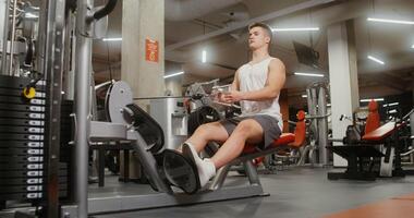 Healthy young man of European appearance is engaged in an exercise machine, shaking his chest muscles, lifting weights with his hands, sitting on a bench photo
