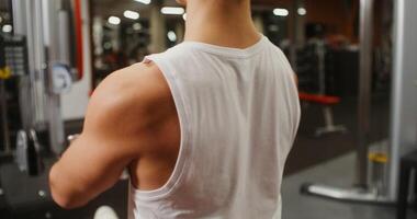 Young man of European appearance is engaged in a strength simulator, lifting heavy weights. Filming from behind, the man's face is not visible photo