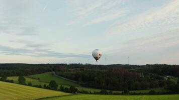 View of a hot air balloon in the sky flying over green fields and forests on a bright summer day, Germany. photo