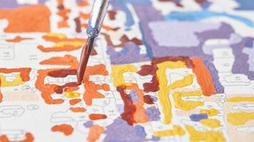 Close up of paintbrush on colorful paint by numbers canvas with vibrant colors and detailed patterns. photo