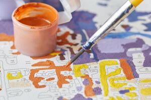 Close up of paint by numbers kit with brush and paint pots in vibrant colors. photo