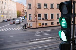 Traffic Light Signaling Green at an Urban Intersection With Vehicles and Pedestrians Navigating the Street in Afternoon Light photo