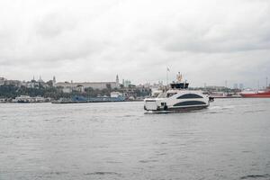 Bosphorus ferry cruising through calm waters with Istanbul skyline in the background on a cloudy day photo