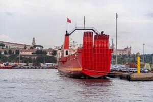 Bosphorus harbor features a large red cargo ship docked against a historical backdrop during the early evening hours photo