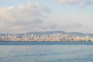 Views of the modern skyline of an island town surrounded by calm waters and distant mountains in Prince Islands during a clear day photo