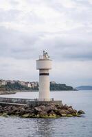 Bosphorus lighthouse standing tall against the coastal skyline on a cloudy afternoon with calm waters and rocky shore photo