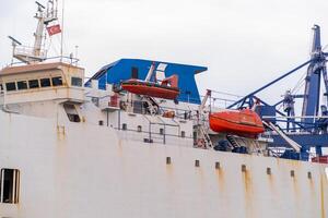 Cargo ship docked at a Bosphorus port showcasing rescue boats and industrial structures on an overcast day photo