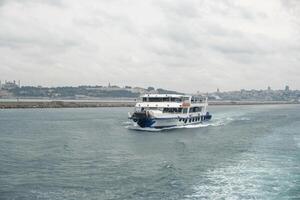 Boat navigating the Bosphorus Strait with Istanbuls skyline in the background during a cloudy afternoon photo