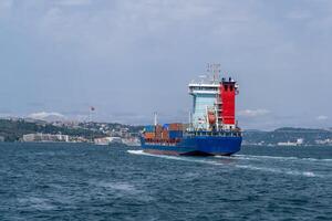 Container ship navigates Bosphorus Strait with city skyline in the background under clear skies photo
