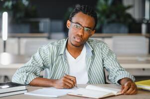 Focused university student taking notes and studying in library photo