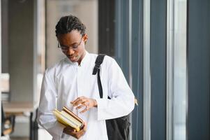 Young male medical student checking his books in university corridor photo