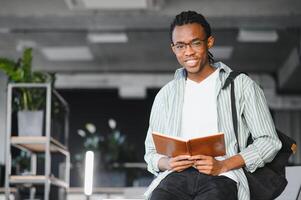 Smiling african american student reading book in university library photo