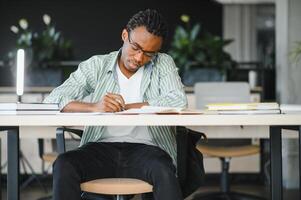 Focused university student studying and taking notes in library photo