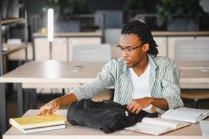 University student taking book from backpack in library photo