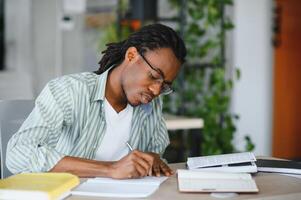 Focused university student taking notes and studying from textbooks photo