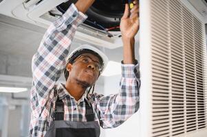 Technician repairing air conditioning system using screwdriver photo