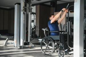 Man with disability exercising with lat pulldown machine in gym photo