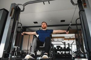 Man with disability, athlete performing seated cable row exercise in gym photo