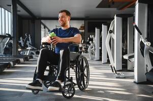 Man with disability recovering and drinking in the gym after workout photo