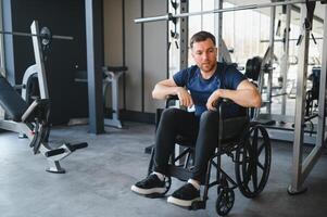 Man with disability resting in wheelchair after workout in gym photo