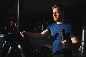 Man exercising on elliptical machine in gym for rehabilitation and recovery photo