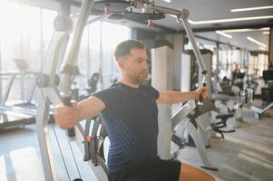 Man doing rehabilitation exercises with pectoral machine in the gym photo