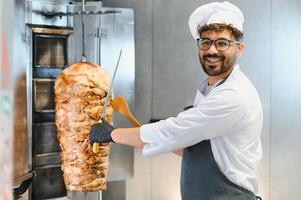 Chef slicing shawarma meat with knife and spatula photo