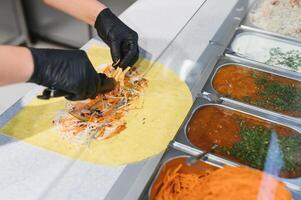 Chef preparing delicious shawarma with various ingredients and sauces photo