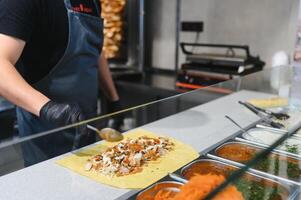 Chef adding sauce to shawarma using spoon in a street food kiosk photo