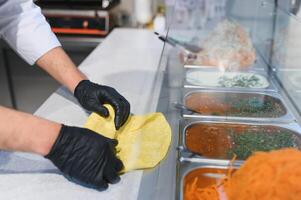 Chef preparing shawarma or kebab using pita bread and ingredients photo