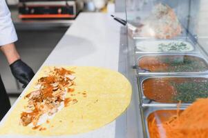 Chef preparing shawarma or kebab with chicken and sauces in a fast food restaurant photo