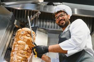 Chef slicing shawarma meat with knife in restaurant kitchen photo