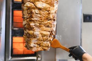 Chef preparing shawarma or kebab on a vertical rotisserie photo