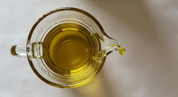 Pouring Cooking Oil From Glass Pitcher Top Down View photo