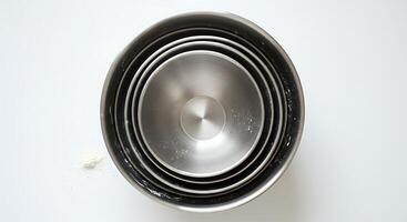 Mixing Bowls Nested with Flour on White Surface Overhead View photo