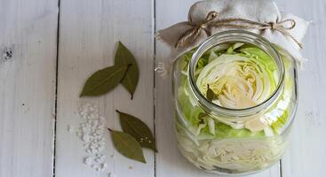 Preparing Cabbage for Fermentation in Glass Jar with Bay Leaves photo