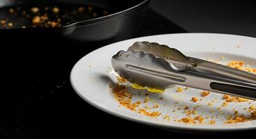 Serving Tongs on Plate with Leftover Food and Pan Cooking photo