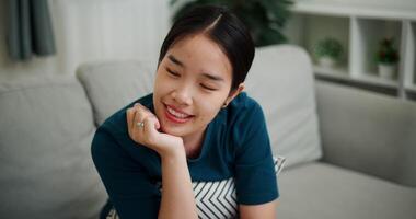 Handheld high angle view shot, Relaxed young woman is sitting on a sofa, enjoying the peace of mind and seems to be thinking about something in a positive mood in living room at home. video