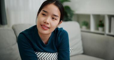 Relaxed woman is sitting on a sofa, enjoying the peace of mind and seems to be thinking about something in a positive mood in living room at home. video